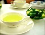 a cup and pot of green tea in a white tea set